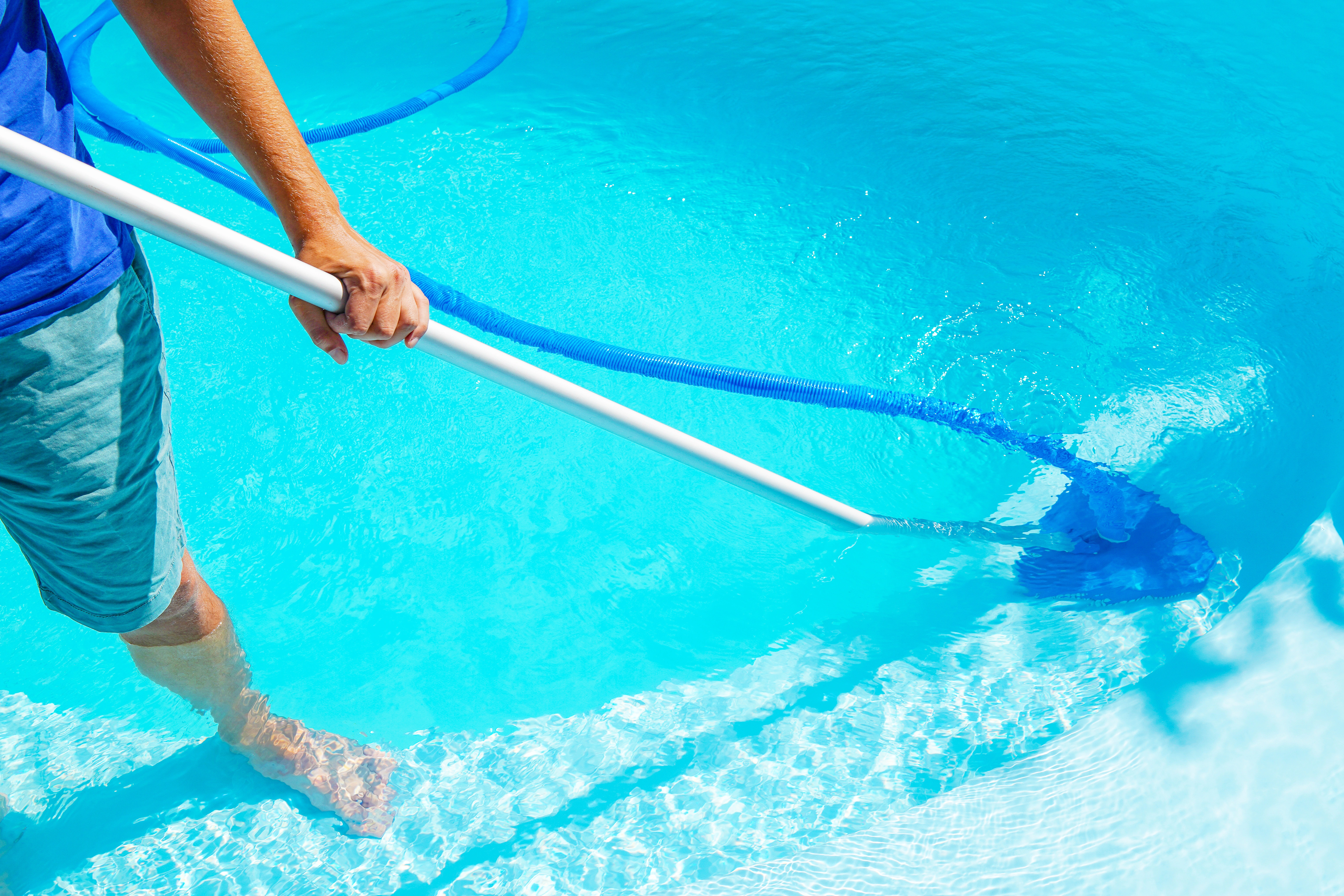 Pool cleaning service in progress around a sparkling swimming pool